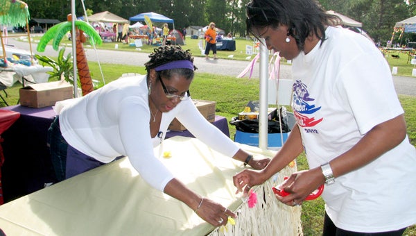 Jennifer Branham, left, and Laquisha Reed, both city employees, decorate the city’s tent with a hula skirt before Relay For Life 2012 kicks off. The city will once again have a team in the event this year.