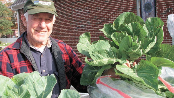 Volunteer Ed Kapinus shows off collards grown in a community garden at East Suffolk Recreation Center. They went to a local church to help with its meals program.