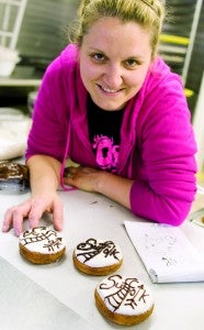 Reeva Luecke shows off a specially-designed Suffolk donut that features railroad tracks and a native arrow to represent the area's first inhabitants.