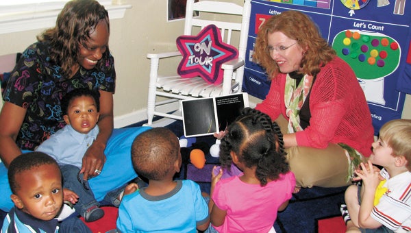 Brenda O’Donnell, Suffolk Early Childhood Development Commission coordinator, reads to students at Michelle Freeman’s in-home daycare center as Freeman looks on. The reading was set up to celebrate Week of the Young Child.