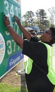 Jackie Hill drops the prices on the sign at Miller Mart on Holland Road on Wednesday. The customer-appreciation initiative, dubbed “We Pump Wednesday,” lets customers get lower-priced gas and have the employees pump it for them.