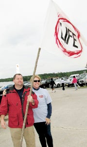 Rick and Kelly Montrose carry the “Life” flag during the Walk for Life at the Suffolk Executive Airport on Saturday morning. More than 200 people attended to support the Crisis Pregnancy Center.
