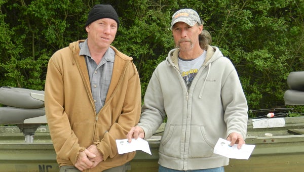 Rod Sickafus of Gates County, N.C., accompanied by Robert Dodge of Suffolk (left), holds up the two checks he received for catching the most in terms of total weight and for catching the biggest single fish at the Suffolk Parks and Recreation’s March of Dimes Bass Fishing Tournament on Saturday at Lone Star Lakes. 