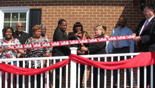 Mayor Linda T. Johnson helps Ricardo and Kimberly Johnson cut the ribbon at the new location of RFK Solutionz as employees and city officials look on. The information-technology company provides training, network security and other services.