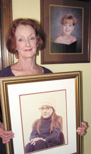 Terry Jones-Brady poses in her home with portraits of her daughters, Heather (in her hands) and Holly (on the wall). Both girls died of cystic fibrosis, and Jones-Brady has written a book about her journey through grief.