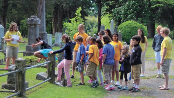 Katie Long, an 11th-grade honors history student Nansemond-Suffolk Academy, shows third-graders from the school around Cedar Hill Cemetery Wednesday. The history walking tour around downtown Suffolk involved two dozen juniors and scores of third-graders.