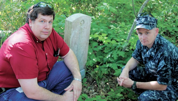Joe Schipper and Ed Fallen crouch next to the grave of Marion Smith, a World War II veteran, who records show may have taken part in the D-Day landings. Smith’s final resting place is among several neglected graves next to Harbour Breeze Apartments.
