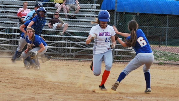 Nansemond-Suffolk Academy eighth-grader Logan Harrell (6) attempts to get the Greenbrier Christian Academy runner out at first base as freshman Brooklyn Carr looks on during the state semifinal at the Petersburg Sports Complex on Thursday. The Lady Saints saw their season end with a 7-0 loss to the Lady Gators.
