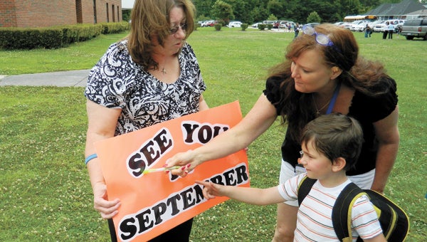 Elephant's Fork Elementary School teachers Peggi Parker-Butler, left, and Kim Petrasek get Early Start student Landon Panzera to spell out and read the sign before his bus picked him up on Friday, the last day of school.