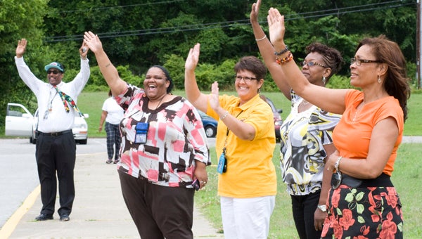 Teachers at John F. Kennedy Middle School wave goodbye as the buses pull away after the last day of school on Friday.