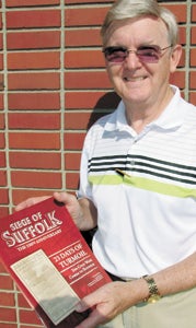 Author Kermit Hobbs shows off a copy of “Siege of Suffolk,” a compilation of a series of stories on the 150th anniversary of the siege that published in the Suffolk News-Herald in April and May.