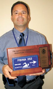 Suffolk Police Lt. John Meston shows off his “Blue Brick” award he earned at the FBI National Academy for completing a 34-mile swim challenge.