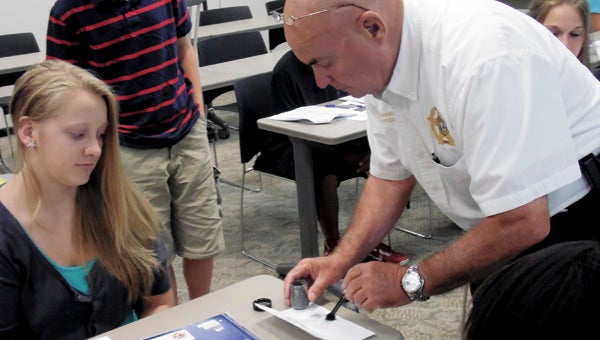Forensic Investigator Bert Nurney of the Isle of Wight Sheriff’s Department shows forensics camp participant Sarah Holland how to dust for fingerprints.