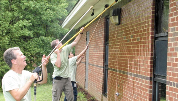 Green Mountain Coffee Roasters employees, from left, Al Bergeron Jr., Darryn Merchant and Damaris Whitfield pressure-wash the outside of the Western Tidewater Free Clinic on Tuesday.