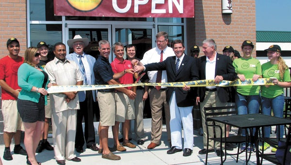 Employees, City Council members and Delegate John Cosgrove help owners Todd Tillery and Chip Kimnach cut the ribbon at Moe’s on Thursday.