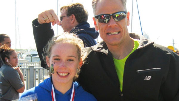 Twelve-year-old Betsy Pollard celebrates with Suffolk New Energy Youth Running Group coach Steve Sheppard after winning the Elizabeth River Run on May 25.