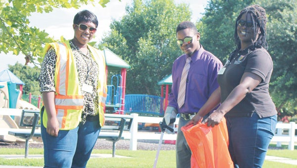Interns Tiara Marshall and Antonio Blackley join Robin Moore, a Suffolk Department of Public Works staffer, at a playground near the Howard Mast Tennis Complex to demonstrate viable projects for a community clean-up campaign.