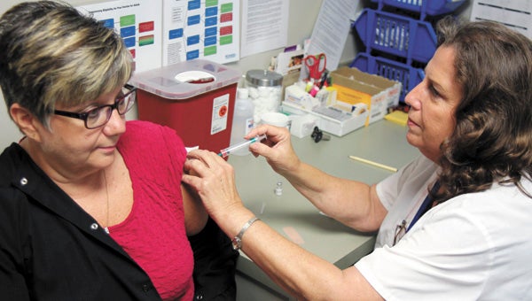 Anne Copeland, a nurse at the Suffolk Health Department, administers a Tdap shot to Jan Jurnigan. Health professionals like Copeland are urging adults to get a Tdap booster shot, if they need one, to protect children.