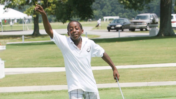 Eleven-year-old Clarence Russell celebrates his putt on the practice green during the Hook-a-Kid on Golf summer program at Sleepy Hole Golf Course this past week.