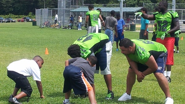 Suffolk Chargers players work with participants of the Peanut City Football Camp last weekend at the JFK Sports Complex. Chargers players in front, from left: Floyd Clark and Carlos Rodriquez; Charger in back: Daryl Greene. (Angela Harper photo)