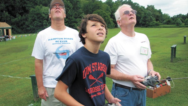 Ronnie Ward, left, and Keith Harrell instruct 12-year-old Parker Bono in the intricacies of flying a radio-control aircraft at the National Model Aviation Day celebration held by the Hampton Roads RC Club.
