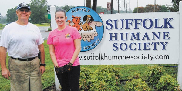 Denis Confer, left, a member of Suffolk Humane Society board of directors, and Rebecca Garber, an area training coach at Potomac Family Dining Group, work to beautify the Suffolk Humane Society on Tuesday, despite the rain.