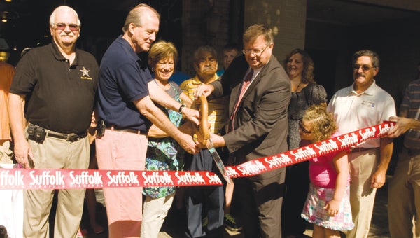 Susan Glover is joined by her husband Butch and city officials, including City Councilmen Charles Parr and Mike Duman and Sheriff Raleigh Isaacs, as she cuts the ribbon in front of her new business, Simply Susan’s Bakery & Café.