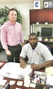 Former Nansemond River High School and Chowan University basketball standout Quinton McDuffie, seated, signs a deal to play basketball professionally in Russia. The deal was arranged by Trey Steele, left, of Hardaway Sports and Legal Representation. McDuffie leaves Oct. 1.