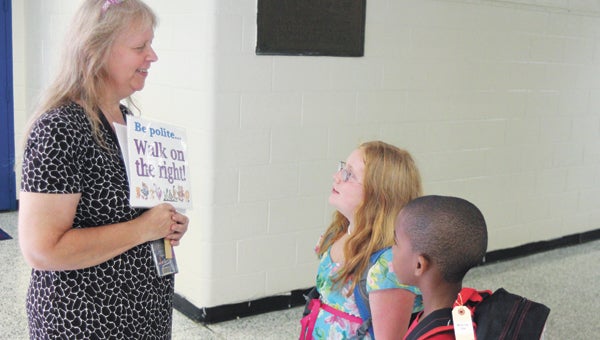 At Driver Elementary School, Marie Scott greets Bella Wulfkuhle, 8, and Aden Judge, 7.