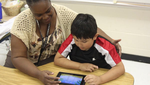 Stephanie Baker-Hill, a special education teacher at Elephant’s Fork Elementary, helps third-grader Juan Noyola navigate an app on one of two new tablets donated to the school.