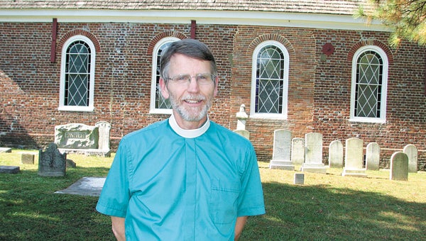 The Rev. Les Ferguson shows off the graveyard and historic building at St. John's Episcopal Church on Kings Highway.