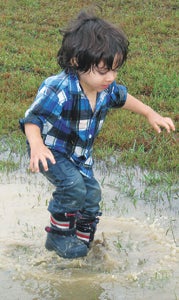 The aptly-named River Johnson, age 2, splashes in a flooded drainage area at the Peanut Festival grounds.