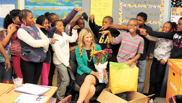 Booker T. Washington Elementary School academic coach Meagan Cunningham celebrates with students Tuesday after receiving a bonanza of school supplies from Suffolk OfficeMax.