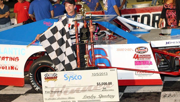 Eddie Johnson celebrates in Victory Lane with his trophy, the checkered flag and a $5,000 check following his win in the Modified Madness 100 event of the NASCAR Whelen All-American Series events at Langley Speedway on Saturday.