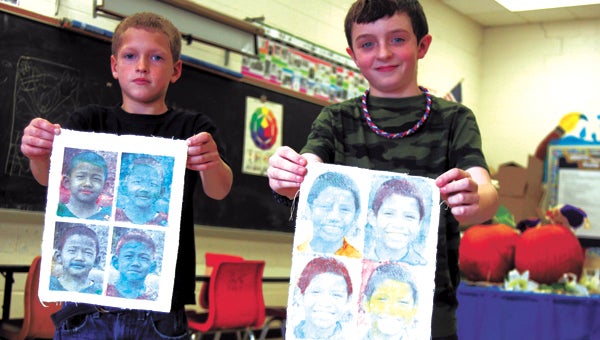 Owen Blanton and Nathan May, fourth-graders at Elephant’s Fork Elementary School, hold up portraits they created of Nepalese children as part of a nationwide project providing mementos of childhood for kids around the world who have been neglected, orphaned or disadvantaged.