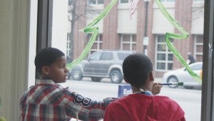 Mack Benn Jr. Elementary School’s Trevon Barnes and Quentin Livingston channel their creative instincts Tuesday, inside a front window of the SunTrust bank on Main Street. The fifth-graders were among 42 students from Suffolk’s public schools joining in an annual tradition of decorating businesses for the holidays. The budding artists will be on the streets again Thursday.