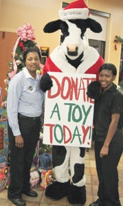 At the North Suffolk Chick-fil-A, manager Tif Adams and team leader Tia Williams drum up support for a Christmas toy drive with help from the store cow.