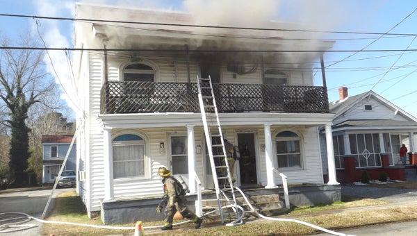 Firefighters work a fire Sunday on Lee Street where a police officer rescued a woman from the burning house.