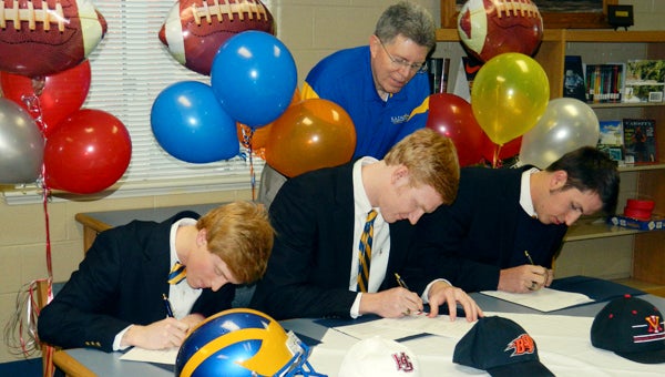 Michael Tyler Lepore, Jared Morse and John Mobley of Nansemond-Suffolk Academy's football team participated in National Signing Day as Saints coach Lew Johnston looks on.