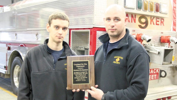 Chuckatuck Volunteer Fire Department firefighters Chris Bailey and Eddie Brock proudly show a plaque from Courtland Volunteer Fire Department, awarded to Chuckatuck VFD for the assistance it rendered during last October’s peanut warehouse fire.
