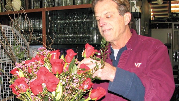 Tim Johnson of Johnson’s Gardens works on an arrangement of roses for Valentine’s Day at his shop on Holland Road on Monday. He and other business owners say Valentine’s-related business has been brisk this year.