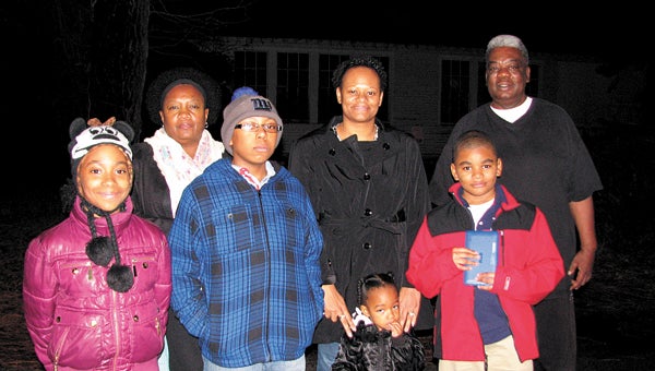 Residents of Huntersville hope their efforts will make a difference in the plan to demolish the old Joseph Gibson School, seen in the shadows behind them, and build new homes in its place. Pictured in back are civic league president Gerri Norman, Caryn Merriweather and Malachai Pork. The youngsters with them are Angel Fields, Jason Merriweather, Jazmyn Brown and Michael Fields, who would be among the many children to benefit from a recreation center if one were to be built in the community.