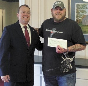 Blake Baker (left) presents Kip West of Keeping Warriors Outdoors a $1,000 check recently. The money helped sponsor a quail hunt for wounded warriors.