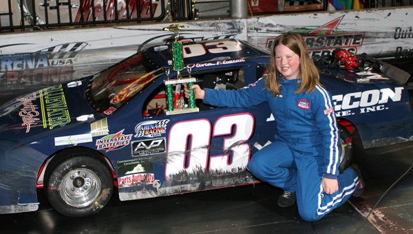Olivia Florian of Suffolk shows off her AAmco/Bluewater Yacht Sales/Precon Marine-sponsored No. 03 with her trophy after her third straight victory in the 30-lap Rainbow Station/Camp Blue Sky Youth Series race at the Arena Racing USA 200 sponsored by Ukrop’s Dress Express at Richmond Coliseum on March 21. (Bill Carr/MotorSports Photo News Service)