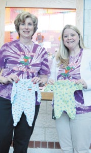 At Creekside Elementary School, bookkeeper Debbie Topping holds up a regular newborn’s onesie, while teacher Anna Russell holds up the one her son Lane wore after he was born premature. The school reportedly raised $4,000 last year and $5,000 in 2012 toward the March of Dimes, which supports preemies.