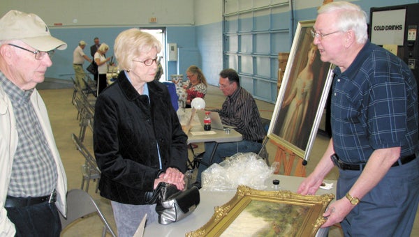 Edward King of Riddick’s Folly, right, appraises a painting brought in by Charles and Holly Lewis to Saturday’s Hidden Treasures fundraiser at the Suffolk National Guard Armory.
