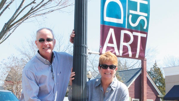 On Smithfield’s Main Street on Wednesday, Mark Hall, team member of Smithfield 2020, and Judy Winslow, director of tourism for Smithfield and Isle of Wight County, stand beneath one of the banners that will be redesigned as part of a contest.