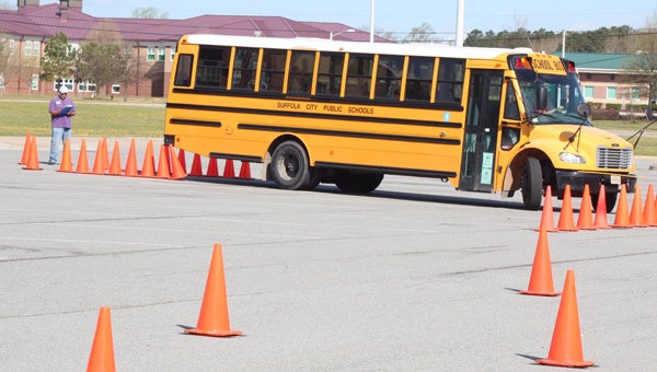 During a school bus rodeo at King’s Fork High School on Saturday, Michelle Woods nudges some traffic cones as she backs down a “chute,” while James Blow Jr. judges her skills.
