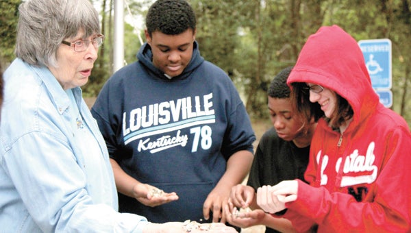Jean Hodges of Suffolk River Heritage shows Forest Glen Middle School seventh-graders Michael Britt, Malique Citizen and Raven Carr some baby oysters.