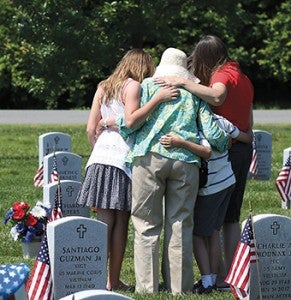 Huddled at the foot of the grave of U.S. Navy Commander Master Chief Richard J. Peters on Monday were, from left, granddaughter Meagan Turner, 11, wife Joan Peters, grandson Mitchell Turner, 9, and daughter Andrea Turner. Richard Peters, a 28-year Navy veteran who served in Korea and Vietnam, died in March 2012.